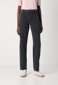 Svarte denimjeans med rett ben. Har en klassisk glidelås og knappelukking. Brukt med lyse sneakers.