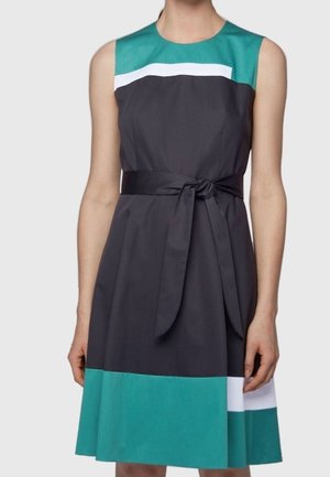 Robe sans manches jusqu'aux genoux avec des blocs de couleur bleu sarcelle, blanc et gris foncé, dotée d'une ceinture assortie nouée à la taille.