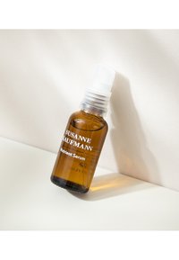 Brązowa szklana butelka z białą pompą, oznaczona etykietą "Sero Nutrientne", ma prosty design i czytelny tekst.