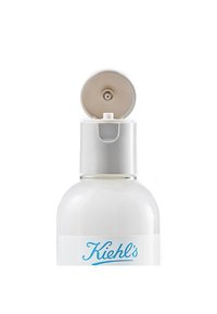 Gjennomsiktig flaske med en hvit etikett og blå tekst, toppet med et lys beige lokk som har en dispenserdyse. Glatt, rund form.