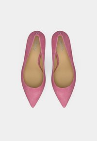 Vaaleanpunaiset mokkanahkaiset ballerinat, joissa on terävä kärki, pyöreä aukko ja sileä pinta. Pienessä takana olevassa korussa on embleemi. Pohja on beigen värinen.