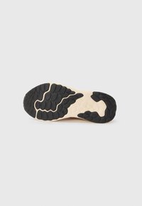 Black and beige rubber outsole featuring textured patterns for traction, with a smooth beige midsole and a defined black heel area.