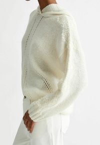 Huppari off-white neuleella, jossa on pitsireunus hihoissa ja avoin neulekuvio. Pehmeä rakenne, löysä istuvuus ja ribatut hihansuut.