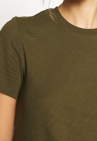 Maglietta a maniche corte verde oliva in morbido cotone, con collo rotondo classico e una texture liscia e leggera.