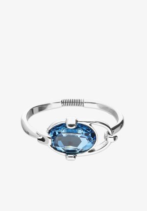 Brazalete de plata con piedra preciosa ovalada azul, acabado pulido y diseño abierto, acentuado con detalles metálicos curvos.