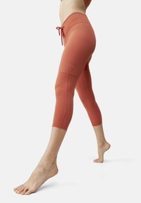 Tette, knelengde leggings i korallfarge, med snor i livet, glatt tekstur og subtile reflekterende detaljer på låret.