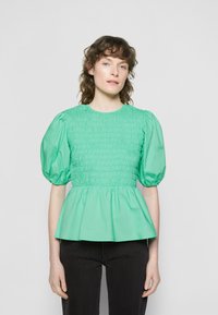 Top verde menta com corpete franzido e mangas bufantes, apresentando uma bainha peplum solta. Feito de um tecido leve e suave.