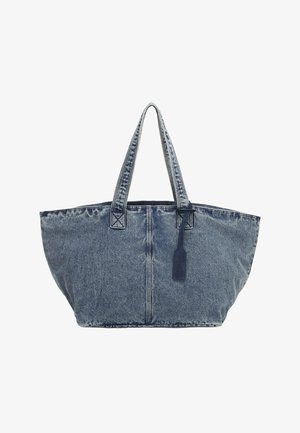 Large blue denim tote bag with double shoulder straps and a hanging navy tag against a white background.