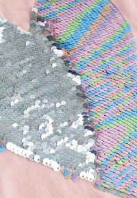 Zilveren en meerkleurige paillettenstof met een roze achtergrond, met verschillende vormen en texturen van de pailletten, waardoor een uniek ontwerp ontstaat.