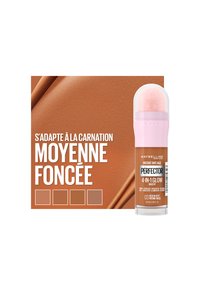 Maquillage Maybelline 4-en-1 Glow en teinte moyen foncé, avec un tube transparent, un applicateur rose doux et un emballage brun avec des accents texturés.