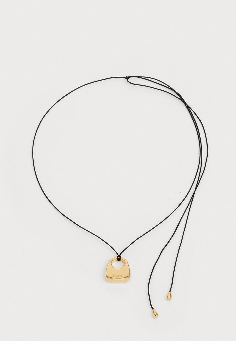 Χρυσό κρεμαστό κόσμημα σε μαύρο κορδόνι. Το μενταγιόν έχει απαλό, στρογγυλό σχήμα με ανάγλυφο κείμενο και δύο χρυσές λεπτομέρειες στις άκρες του κορδονιού.