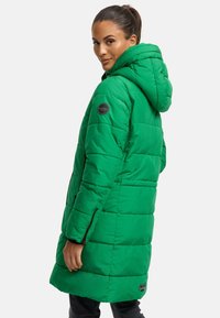 Abrigo acolchado verde con capucha, que presenta un diseño de acolchado, cremalleras laterales y un parche circular de la marca en la manga. Largo, aislante y ajustado.