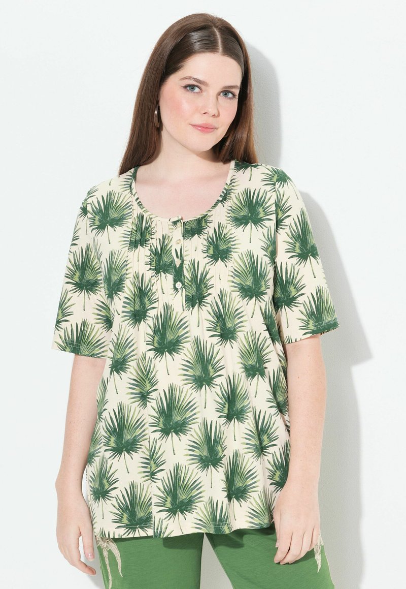 Camiseta de manga corta en crema con estampado de hojas de palma verdes, con escote redondo y detalles de botones. Tela suave y ligera.