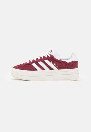 Baskets Adidas Gazelle en daim bordeaux avec des bandes blanches, des lacets blancs et une épaisse semelle plateforme écrue, vues de côté.