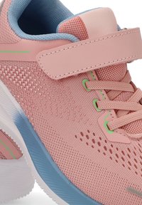 Zapatilla deportiva rosa con forro interior azul claro, detalles verdes, tejido de malla, cordones y una correa de Velcro encima de la lengüeta.