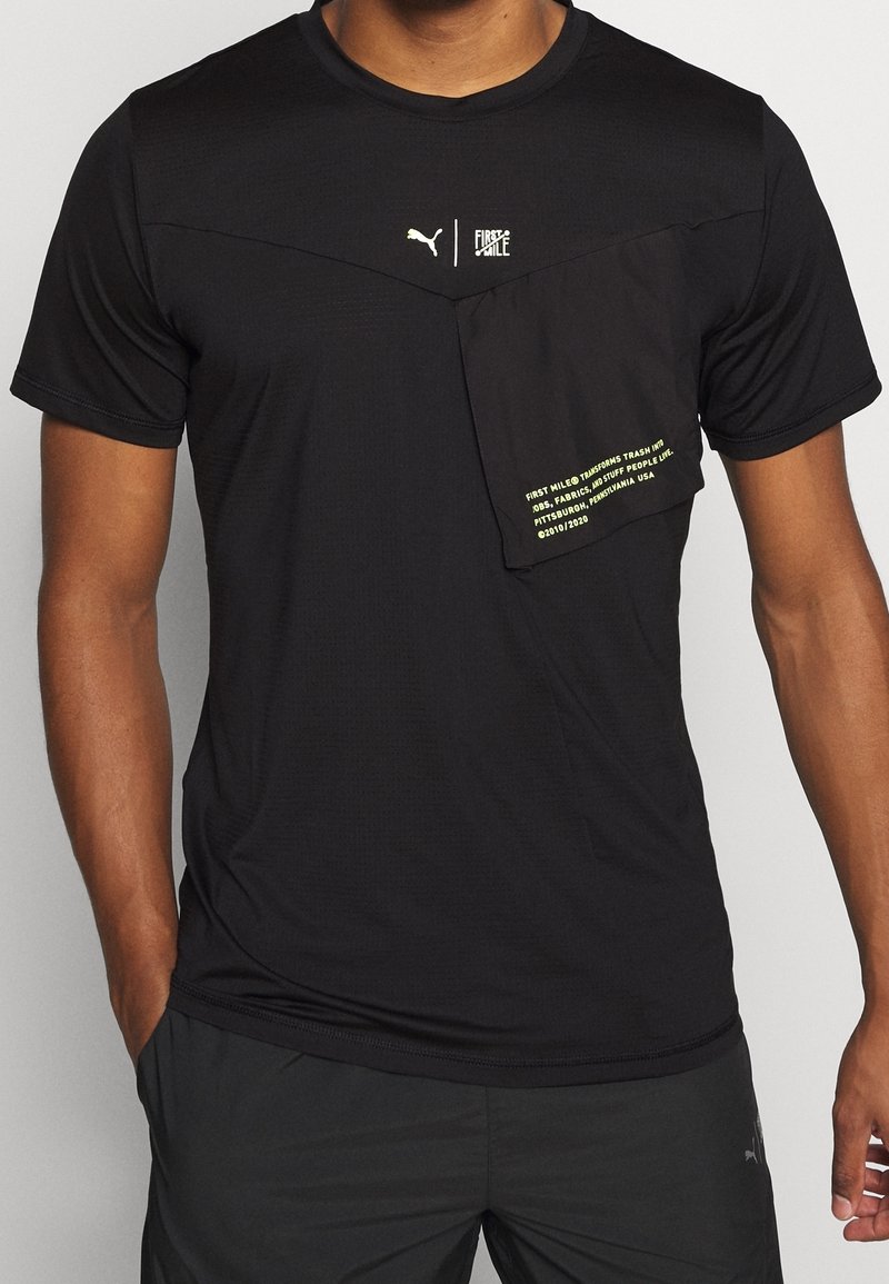 Svart atletisk t-shirt med texturerat tyg, har en framficka med neontext och Puma-logotyp. Kortsleeve, rund halsringning.