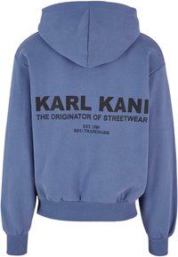 Kék pamut kapucnis pulóver, nagy fekete grafikával a hátsó oldalon, rajta a "KARL KANI A STREETWEAR EREDETE" felirattal és bordás mandzsettával.