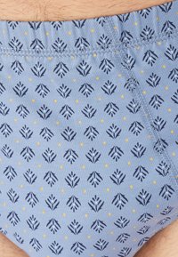 Bañadores azules con un patrón floral náutico repetido en navy con pequeños puntos amarillos, tela texturizada y cinturilla cosida.