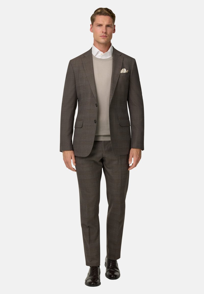 Completo grigio testurizzato slim fit, indossato sopra un maglione grigio chiaro. Camicia bianca sotto e un fazzoletto bianco nella giacca.