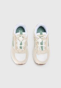 Beige und weiße Sportschuhe aus Mesh und Wildleder, mit grünen Akzenten, runden Schnürsenkeln und einer gepolsterten Sohle.