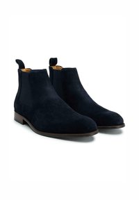 Navy suede Chelsea boots featuring elastic side panels, looped pull tabs, and a smooth leather sole. Each boot has a tapered toe design.