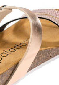 Sandalias de cuero rosa claro con plantilla de corcho. Presentan una correa texturizada y un delgado acento metálico. Diseño de suela plana.