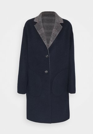 Manteau en laine bleu marine avec deux boutons noirs et un col à revers cranté gris à carreaux, doté de deux grandes poches avant arrondies.