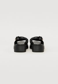 Sorte lær sandaler med flat såle, stropdesign og spenndetalj. Glatt tekstur med minimalistisk design og bred passform.