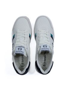 Fehér sportcipők sima bőrfelülettel, türkiz és sötétkék csíkokkal, fűzős kialakítással, és logóval a nyelvén.