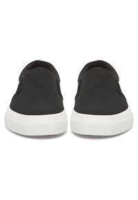 Pár čiernych slip-on tenisiek s bielymi gumovými podrážkami, zobrazený zozadu na bielom pozadí.
