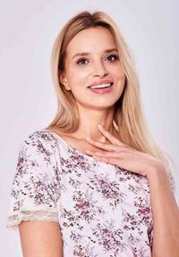 Bluzka w kwiatowy wzór z jasnoróżowej tkaniny, z krótkimi rękawami wykończonymi koronką. Gładka faktura i luźny krój.