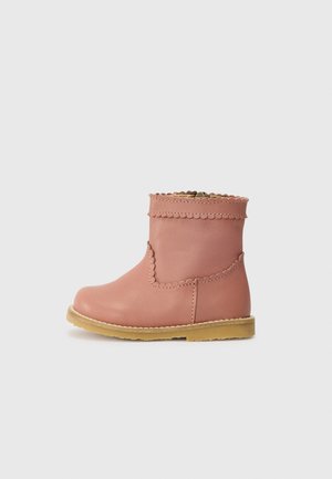 Botas de tornozelo em pele rosa com borda superior em forma de onda, detalhe na costura lateral e sola de borracha em tom de caramelo. Fecho com zip no lado interior.