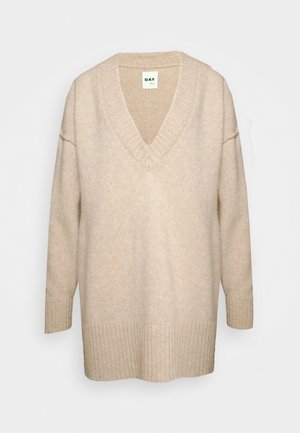 Pull en tricot beige avec un col en V, des manches longues, des poignets côtelés et un ourlet droit, fabriqué à partir d'un mélange de laine douce.