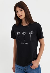 Black cotton t-shirt featuring three white outlined flowers and the phrase "bloom wildly" below. Short sleeves and a round neckline.