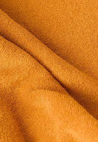 Close-up of textured orange terry cloth fabric with visible loops and soft folds.