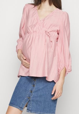 Blouse rose texturée avec un décolleté en V, taille froncée et manches longues élastiques, associée à une jupe crayon en denim avec des détails de boutons.