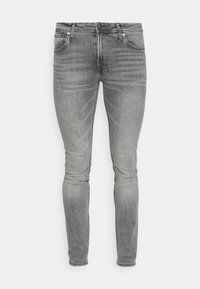 Jeans skinny de mezclilla gris con una textura suave, diseño de cinco bolsillos y un desvanecimiento sutil. Presenta herrajes de metal y un cierre de cremallera.