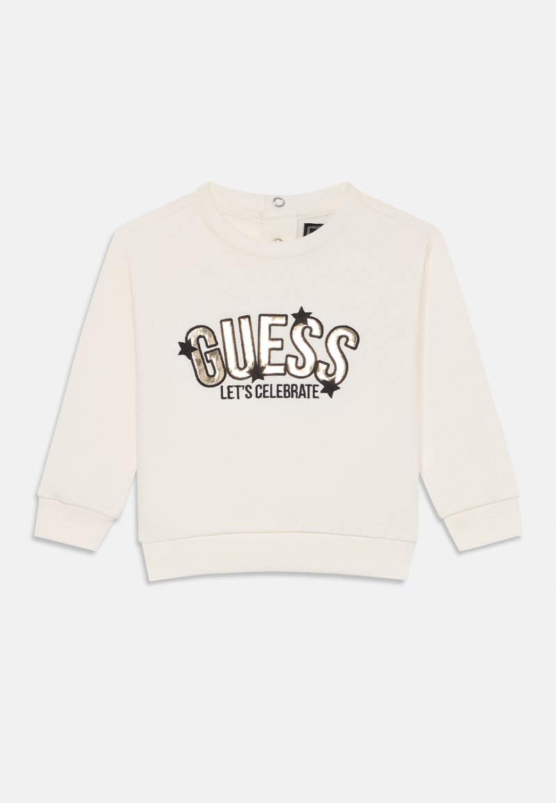 Sweatshirt blanc à manches longues, col rond, présentant le texte brodé en noir et or "GUESS LET'S CELEBRATE" et des accents d'étoiles.