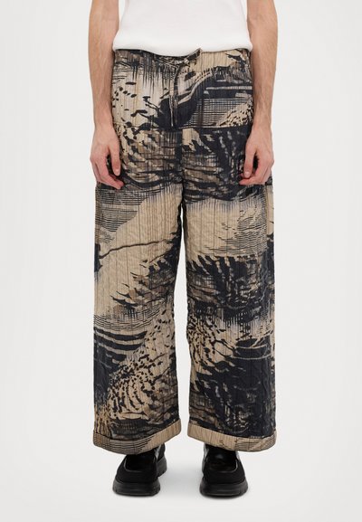 Wide-leg trousers featuring a textured, abstract print in beige and black. Includes an elastic waistband and drawstring closure.
