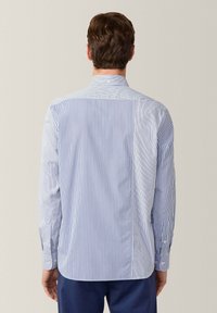 Blau-weiß gestreifte Button-Down-Bluse mit langen Ärmeln, ausgestattet mit einem Kragen, Rückensattel und geknöpften Manschetten. Aus glattem Baumwollmaterial.