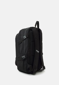 Sac à dos noir avec des côtés rembourrés et texturés, des bretelles réglables et des accents en maille. Caractérisé par un logo et plusieurs compartiments.