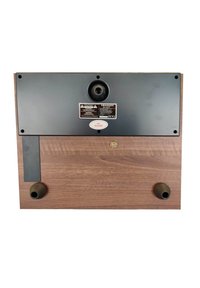 Base de tourne-disque Crosley avec une finition en bois noyer, panneau en métal noir, deux pieds en caoutchouc, port d'entrée et étiquette de précaution.