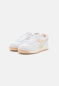 White and beige sneakers with a perforated upper, featuring textured panels, lace closure, and a cushioned cream interior.