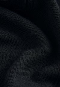 Nahaufnahme eines schwarzen Strickstoffs, der eine weiche Textur und ein feines geripptes Muster mit sanften Falten zeigt.
