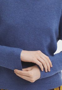 Blå stickad tröja med rund halsringning och ribbade muddar. Mjuk textur, avslappnad passform och medeltjockt tyg.