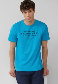 Kurzärmliges T-Shirt mit Rundhalsausschnitt in leuchtendem Blau, aus weichem Material gefertigt. Auf der Vorderseite befindet sich schwarzer Text mit dem Markennamen und dem Slogan.