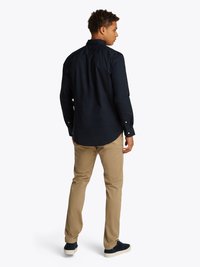 Marineblaues Hemd mit Kragen, kombiniert mit khakifarbenen Hosen. Glatte Stofftextur, normaler Schnitt und Rückensattel-Details sind sichtbar.