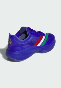 Scarpa atletica blu con strisce rosse, bianche e verdi sul lato, tomaia in mesh testurizzato, suola spessa e logo dorato vicino al tallone.