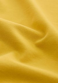 Soft yellow fabric with fine knit texture and gentle folds creating subtle shadows and highlights.