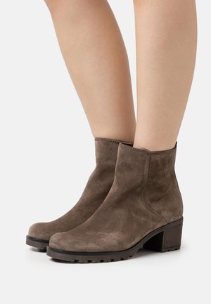 Braune Wildleder-Ankle-Boots mit runder Spitze, Blockabsatz und strukturiertem Fußbett. Sie zeichnen sich durch klare Linien und minimale Nähte aus.